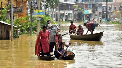 Locals use boats to cross the waterlogged street due to flooding of rivers in Ghatal on Monday. ANI