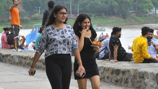 Two young girls take a stroll around the lake as they enjoy a plate of chaat at Sukhna Lake in Chandigarh on August 1.(Keshav Singh/Hindustan Times)