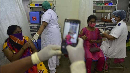 A beneficiary gets photographed while a BMC medical staff inoculates her against Covid-19 at Nair Hospital, Bombay Central, in Mumbai on Friday, July 30. (Anshuman Poyrekar/HT photo)