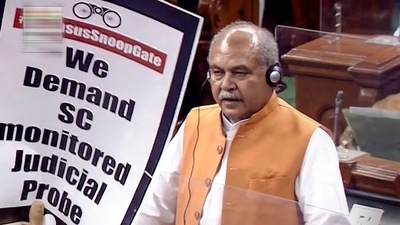 Union minister Narendra Singh Tomar speaks in the Lok Sabha while an Opposition leader shows a placard on Wednesday. (LSTV/PTI Photo) (PTI) Union minister Narendra Singh Tomar speaks in the Lok Sabha while an Opposition leader shows a placard on Wednesday. (LSTV/PTI Photo) (PTI)