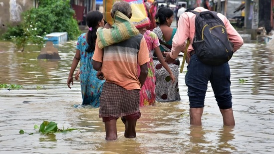 People walk through the floodwater with their belongings after heavy rainfall hit Udayanarayanpur, Howrah, in Kolkata on July 3. (ANI)