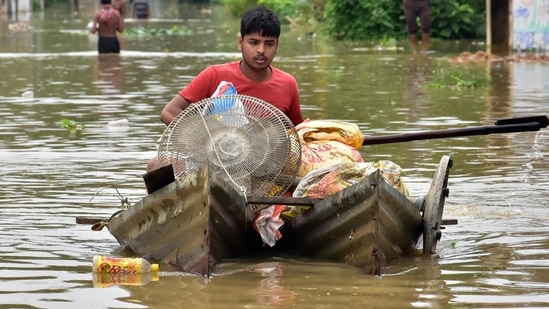 A man carries his goods to a safer place on a makeshift tin boat as heavy rains lead to waterlogging in Howrah on July 3.(ANI)