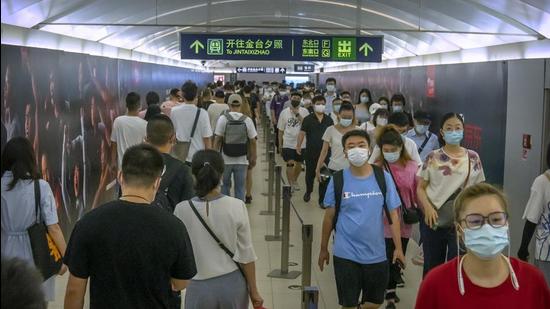 People wearing face masks walk through a subway station during the morning rush hour in Beijing on August 4, 2021. (AP)