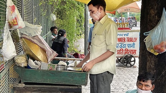 In his 40s, Raju is dressed formally in grey pants and a collared shirt with sleeves rolled up to the elbows.