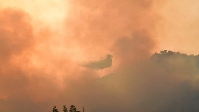An aircraft drops water during a wildfire in ancient Olympia, western Greece on August 5.  (AP)