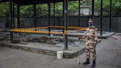 A security person stands guard near a pyre inside a crematorium in Delhi where a 9-year-old girl was cremated. (AP)