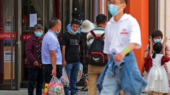 People wearing face masks to help curb the spread of the coronavirus talk to each other outside a grocery store at the Wangfujing shopping district in Beijing.(AP File Photo)