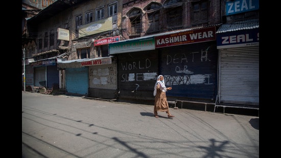 A Kashmiri woman walks at a closed market in Srinagar on the second anniversary of revocation of Art 370 on Thursday. (AP)