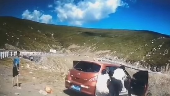 Two passengers try to stop car from rolling down the hill (Asiawire/Daily Mail)