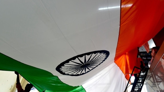 Staff at a flag shop in Mumbai inspect the 14-feet by 21-feet Indian Tricolour made for the upcoming Independence Day, at Byculla. (Anshuman Poyrekar/Hindustan Times)