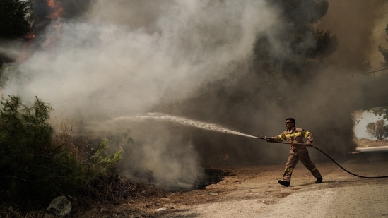 A Greek firefighter works to extinguish a wildfire that hit the Agios Stefanos region, north of Athens, Greece on August 6. (Nick Paleologos/Bloomberg)