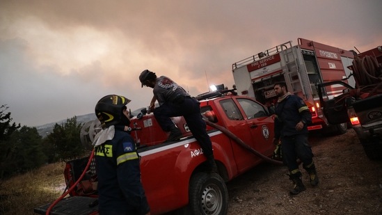 Greek firefighters work from a fire truck as they prepare to extinguish a wildfire in the Taxiarches region, near Athens, Greece, on Augsut 6. (Konstantinos Tsakalidis/Bloomberg)