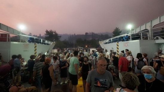 People embark a ferry during an evacuation from Kochyli beach as wildfire approaches near Limni village on the island of Evia, about 160 kilometers (100 miles) north of Athens, Greece on August 6. 2021.(AP)