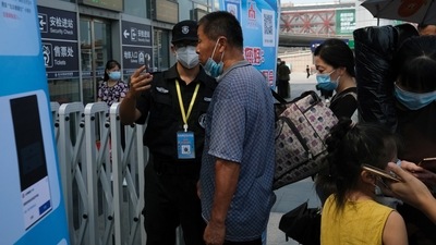 A security guard holds a phone as he scans face of a man for checking his health status at the entrance of a railway station, following new cases of Covid-19 in Beijing, China. (Reuters)
