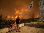 Local residents look at the wildfire approaching the village of Gouves on Evia (Euboea) island, second largest Greek island on August 8. Local residents look at the wildfire approaching the village of Gouves on Evia (Euboea) island, second largest Greek island on August 8.