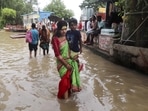 People wade through the waterlogged street as the risen water level of the Ganga river entered the road, following heavy rains, at the Assi Ghat in Varanasi.(PTI)