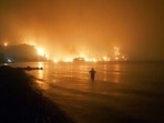 A man watches as wildfires approach Kochyli beach near Limni village on the island of Evia, about 160 kilometers (100 miles) north of Athens, Greece. A man watches as wildfires approach Kochyli beach near Limni village on the island of Evia, about 160 kilometers (100 miles) north of Athens, Greece.