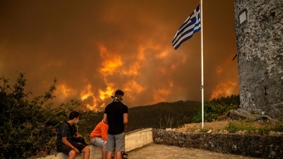 Local residents look at the wildfire approaching the village of Gouves on Evia (Euboea) island, second largest Greek island on August 8. (AFP) Local residents look at the wildfire approaching the village of Gouves on Evia (Euboea) island, second largest Greek island on August 8. (AFP)