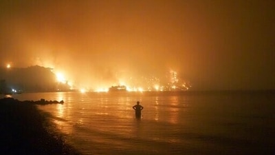 A man watches as wildfires approach Kochyli beach near Limni village on the island of Evia, about 160 kilometers (100 miles) north of Athens, Greece. (AP)