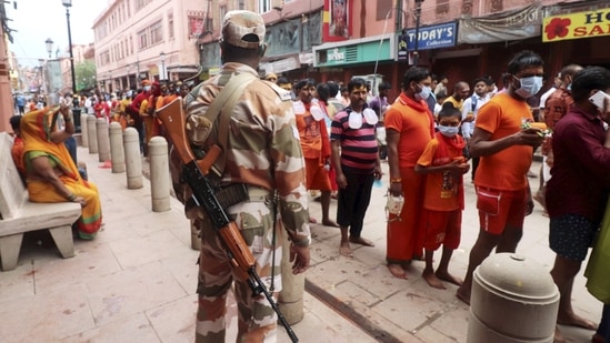 A security personal stands guard as devotees stand in a queue to offer prayers at Kashi Vishwanath temple, in Varanasi,(PTI Photo)