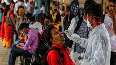 A health worker collects a swab sample from a traveller as they scan people as a precaution against Covid-19 at a railway station in Mumbai, India. (AP) A health worker collects a swab sample from a traveller as they scan people as a precaution against Covid-19 at a railway station in Mumbai, India. (AP)