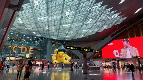 Passengers wearing protective face masks amid the Covid-19 outbreak walk at the Hamad International Airport, Doha, Qatar.(Reuters)