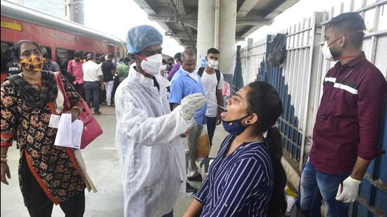 A BMC health worker collects swab samples for Covid-19 test of passengers arriving from outstation trains at Dadar Station. (Anshuman Poyrekar/HT PHOTO)