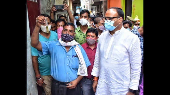 A resident of Balu Adda shows a water sample to UP law minister Brajesh Pathak. (Deepak Gupta/HT Photo)