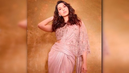 Nora Fatehi turned model for ace designer Tarun Tahiliani as she posed in a metallic rustic pink saree.(Instagram/@norafatehi)