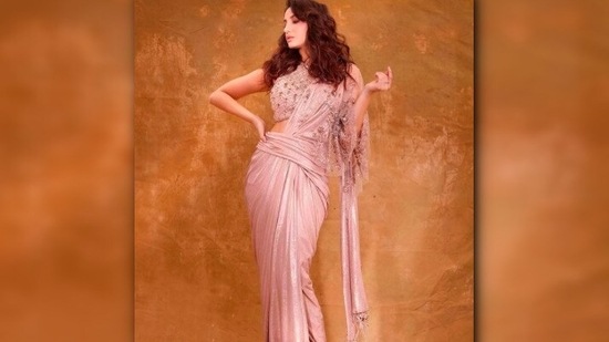 Draping the saree in a fancy way, Nora Fatehi teamed it with a high-neck embellished blouse.(Instagram/@norafatehi)