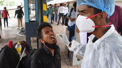 A health worker collects swab samples for Covid-19 test of passengers arriving from outstation trains at Dadar station. (HT PHOTO) A health worker collects swab samples for Covid-19 test of passengers arriving from outstation trains at Dadar station. (HT PHOTO)