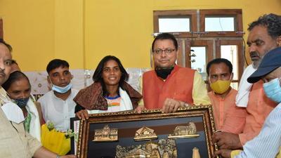 Chief minister Pushkar Singh Dhami felicitates hockey India player Vandana Kataria at her residence in Haridwar district of Uttarakhand on Thursday, August 12 . (HT photo)