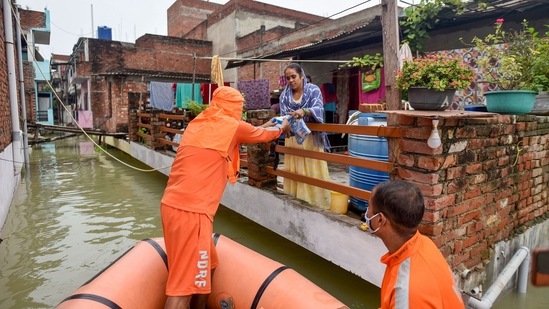 District administration officials provide relief material to flood-affected people in Om Gaytri Nagar area, in Prayagraj on August 12.(PTI)