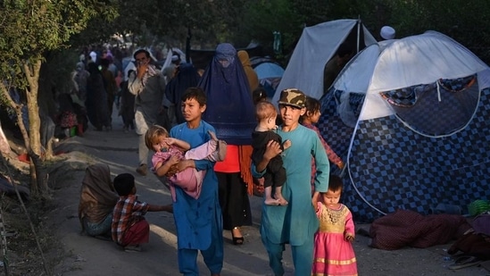 Internally-displaced Afghan families, who fled from Kunduz, Takhar and Baghlan province due to battles between Taliban and Afghan security forces, walk past their temporary tents in Kabul on August 11.(AFP Photo)