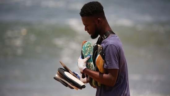 Ivorian painter Aristide Kouame 26, who paints optical effects artworks with worn soles, holds used flip-flops picked up among the garbage on a beach in Abidjan, Ivory Coast.(REUTERS)