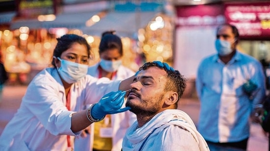 A health worker collects a nasal swab sample from a devotee to test for Covid-19.(AFP)