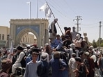 Taliban fighters stand on a vehicle along the roadside in Kandahar on Friday.(AFP Photo)