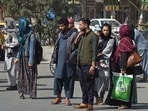 Afghan people stand along the roadside as they wait for taxi in Kabul.