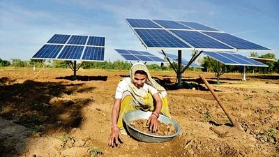 A farmer works near solar panels installed in the field to help pump water for irrigation purposes, in Gujarat’s Dhundi. (AFP) A farmer works near solar panels installed in the field to help pump water for irrigation purposes, in Gujarat’s Dhundi. (AFP)