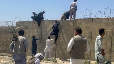 Men try to get inside Hamid Karzai International Airport in Kabul, Afghanistan on Monday. (REUTERS) Men try to get inside Hamid Karzai International Airport in Kabul, Afghanistan on Monday. (REUTERS)