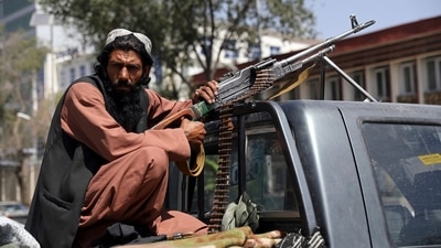 A Taliban fighter sits on the back of vehicle with a machine gun in front of the main gate leading to the Afghan presidential palace, in Kabul, Afghanistan on Monday.&nbsp; (AP / Rahmat Gul)
