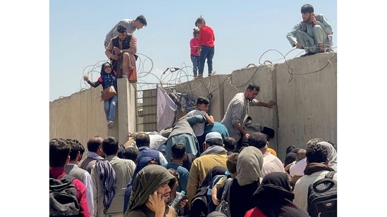 A man pulls a girl to get inside Hamid Karzai International Airport in Kabul, Afghanistan on August 16, 2021. Several photographs and videos on social media show&nbsp;Afghans crowding&nbsp;the airport trying to get out of the country after Taliban insurgents entered the capital on Sunday.&nbsp;(REUTERS)