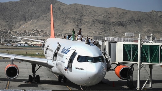 People climb atop a plane as they wait at the Kabul airport on Monday to flee Afghanistan,(AFP)