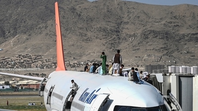 Afghan people climb atop a plane as they wait at the Kabul airport in Kabul on Monday. (AFP Photo) Afghan people climb atop a plane as they wait at the Kabul airport in Kabul on Monday. (AFP Photo)