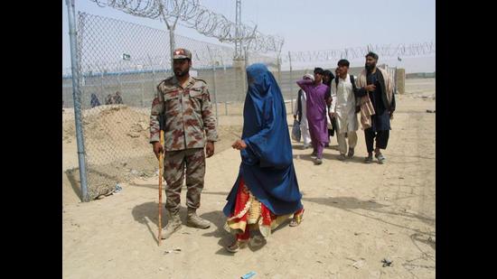 An Afghan woman walking past a Pakistani paramilitary personnel, as she along with others enter Pakistan via Friendship Gate crossing point at the Pakistan-Afghanistan border town of Chaman on Tuesday. (Reuters)