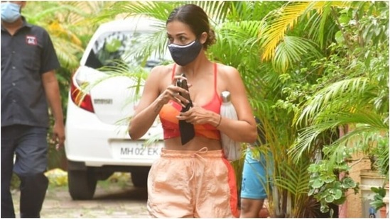 Malaika added colours to her workout clothes for the gym look. She wore a strappy sports bra adorned with different orange-hued stripes. The crop top featured a scooped neckline and flaunted her toned midriff.(Varinder Chawla)