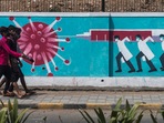 People walk past a wall mural depicting medical staff as frontline Covid-19 warriors in Mumbai.