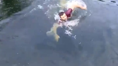 The image shows a man swimming towards the drone to rescue it. (Screengrab)