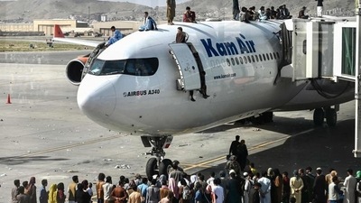 Afghan people climb atop a plane as they wait at the Kabul airport on August 16 (AFP/Used only for representation) Afghan people climb atop a plane as they wait at the Kabul airport on August 16 (AFP/Used only for representation)