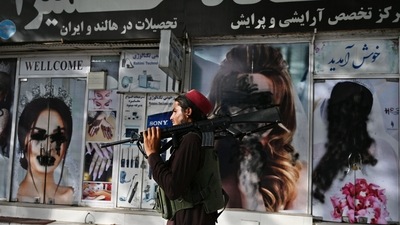A Taliban fighter walks past a beauty salon with images of women defaced using spray paint in Shar-e-Naw in Kabul. (AFP) A Taliban fighter walks past a beauty salon with images of women defaced using spray paint in Shar-e-Naw in Kabul. (AFP)